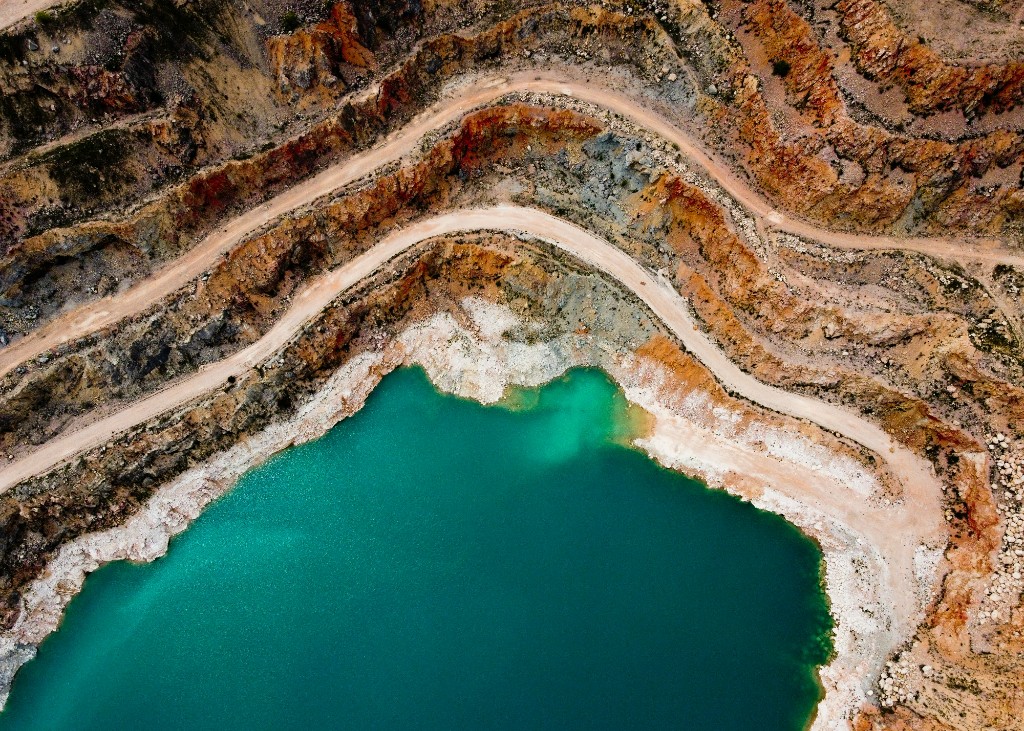 Aerial view of terraced open-pit workings with a deep turquoise water pool, illustrating mining and industrial water settings.